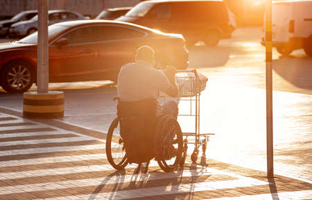 Person with a physical disability pushing cart in front of himself at supermarket parkingの写真素材