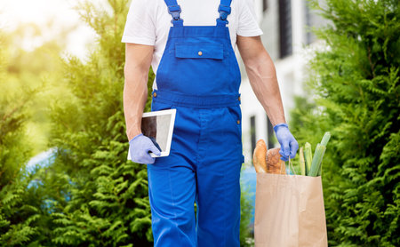 Young courier wearing a protective mask and gloves delivers goods during quarantine