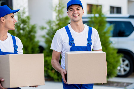 Two removal company workers are loading boxes into a minibus.