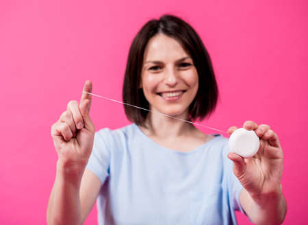 Beautiful young woman use dental floss on pink backgroundの写真素材