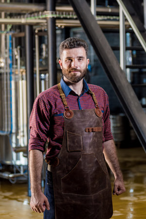 Young male brewer in leather apron at modern brewery factoryの写真素材