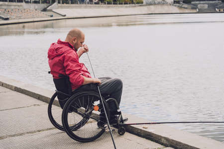 Person with a physical disability in a wheelchair fishing from fishing pier.の写真素材