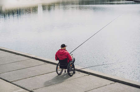 Person with a physical disability in a wheelchair fishing from fishing pier.の写真素材
