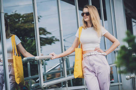 Young beautiful woman with linen eco bag on city background.