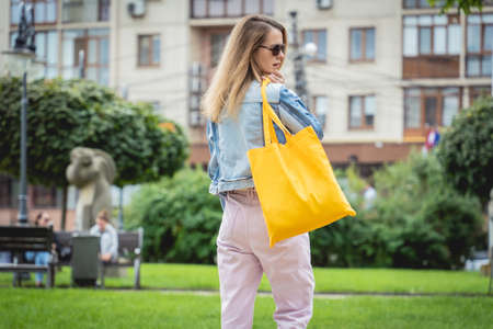 Young beautiful woman with linen eco bag on city background.の写真素材