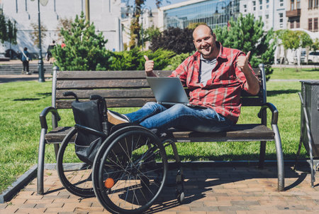 Freelancer with a physical disability in a wheelchair working at the park