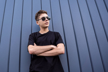 Portrait of a fashion young man leaning against a blue wall