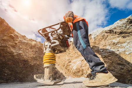 Worker uses a portable vibration rammer at construction of a power transmission substationの写真素材