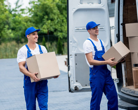 Two removal company workers unloading boxes from minibus into new homeの写真素材