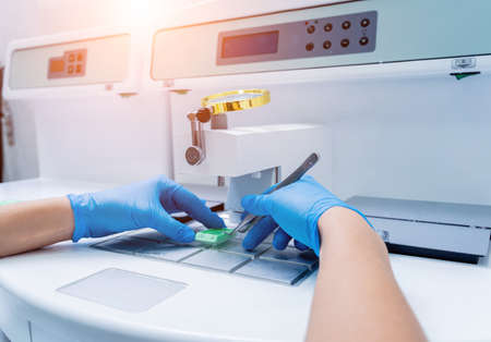 Laboratory assistant works at paraffin wax dispenser tissue embedding machine.の写真素材