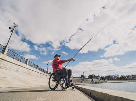Person with a physical disability in a wheelchair fishing from fishing pier.の写真素材