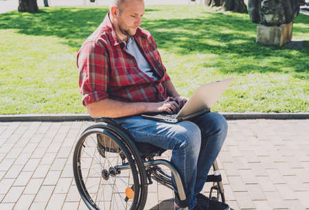 Freelancer with a physical disability in a wheelchair working at the parkの写真素材