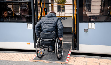 Person with a physical disability enters public transport with an accessible ramp.