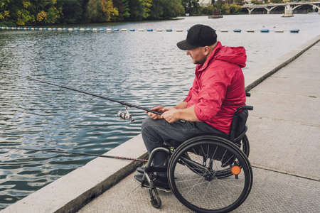 Person with a physical disability who uses wheelchair fishing from fishing pier.の写真素材