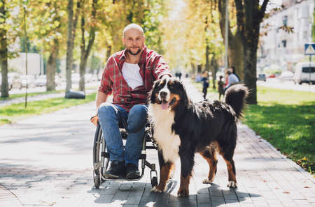 Happy young man with a physical disability who uses wheelchair with his dog.の写真素材
