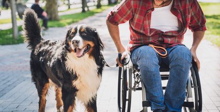 Happy young man with a physical disability who uses wheelchair with his dog.