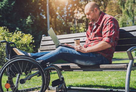 Freelancer with a physical disability who uses wheelchair working at the park