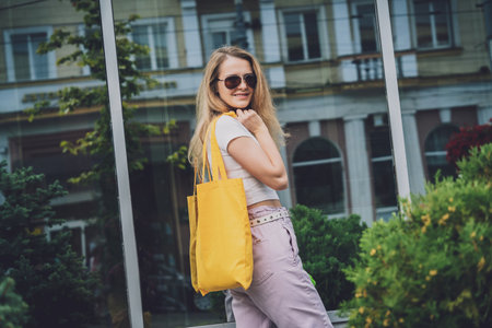 Young beautiful woman with linen eco bag on city background.の写真素材