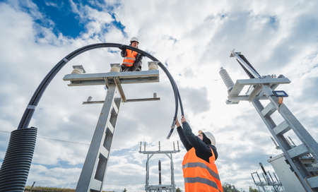 Two electrician builder workers installing high-voltage cableの写真素材