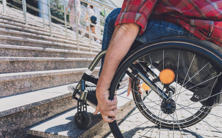 Young man with a physical disability who uses wheelchair in front of the stairsの写真素材