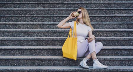 Young beautiful woman with linen eco bag on stairs background.の写真素材