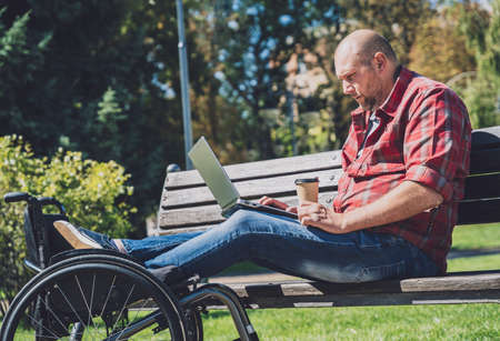 Freelancer with a physical disability who uses wheelchair working at the parkの写真素材