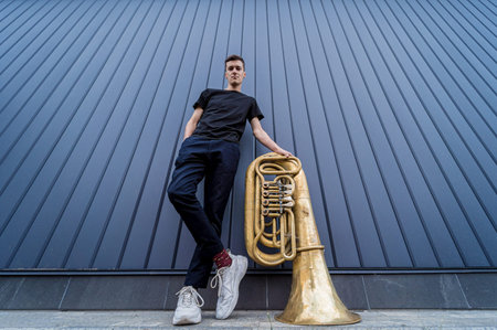 Young street musician playing the tuba near the big blue wall