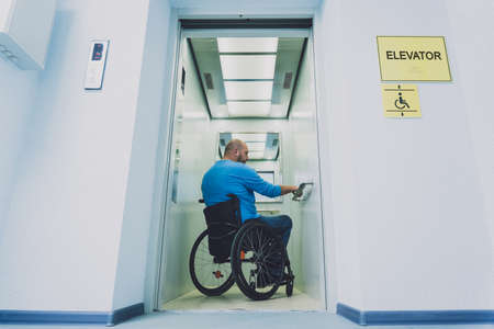 Person with a physical disability who uses wheelchair using lift in buildingの写真素材