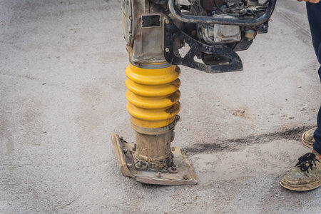Worker uses a portable vibration rammer at construction of a power transmission substation