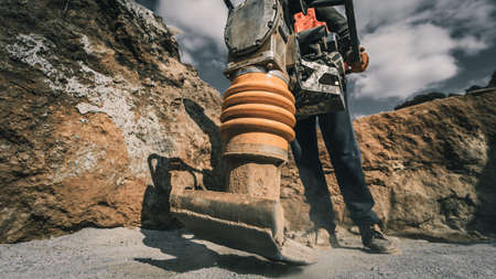 Worker uses a portable vibration rammer at construction of a power transmission substationの写真素材
