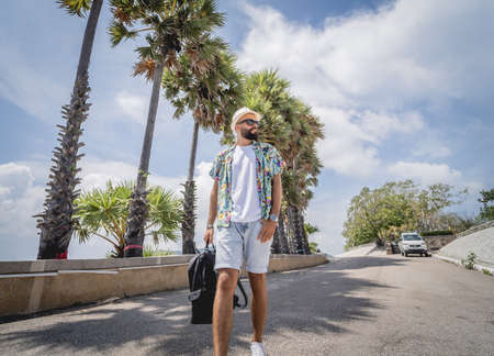 Young traveler man at summer holiday vacation with beautiful palms and seascapes at backgroundの写真素材