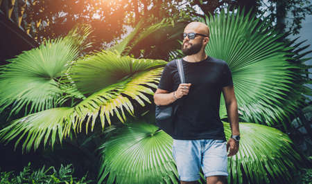 Portrait of a fashion young man at beautiful green leaves background in jungleの写真素材
