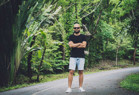 Portrait of a fashion young man at beautiful green leaves background in jungleの写真素材