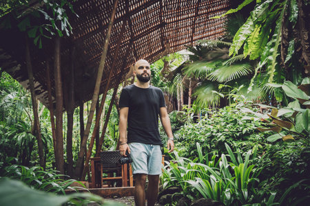 Portrait of a fashion young man at beautiful green leaves background in jungleの写真素材