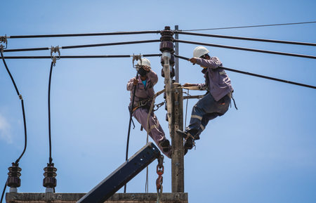 Electricians is repairing high voltage wires on electric power pole