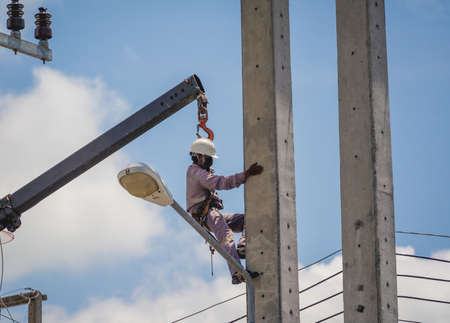 Electricians is repairing high voltage wires on electric power poleの写真素材