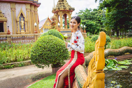 Beautiful Asian girl at big Buddhist temple dressed in traditional costumeの写真素材