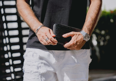 Young businessman holding wallet in his hands against his modern home with garage and car