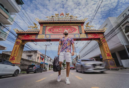 A young man travels with a backpack along the street of an asian cityの写真素材