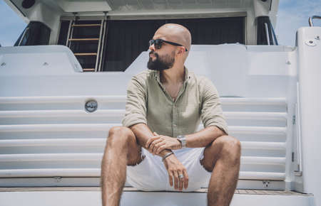 Portrait of a fashion young man posing at marina and yahts backgroundの写真素材