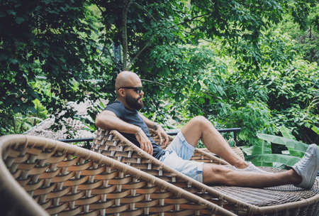 Portrait of a fashion young man at beautiful green leaves background in jungleの写真素材