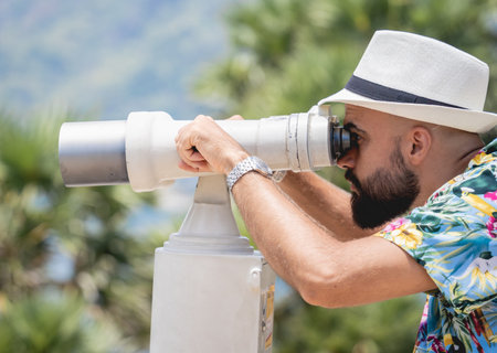 Man watching through binoculars telescope standing on observation point