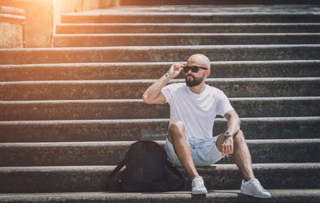 Lonely young handsome man sitting on stairs at the parkの写真素材