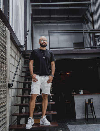 A young man in t-shirt and shorts on the stairs at city streetsの写真素材