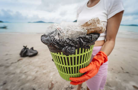 A female ecologist volunteer cleans the beach on the seashore from plastic and other wasteの写真素材