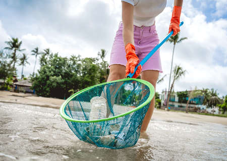 A female ecologist volunteer cleans the beach on the seashore from plastic and other wasteの写真素材