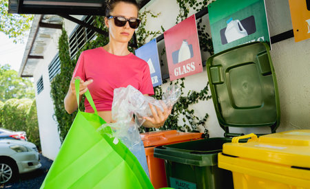 A young beautiful girl throws sorted garbage into special bins