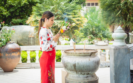 Beautiful Asian girl at big Buddhist temple dressed in traditional costumeの写真素材