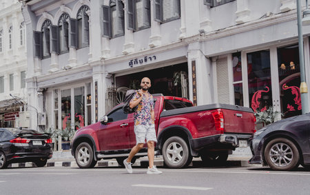 A young man travels with a backpack along the street of an asian cityの写真素材