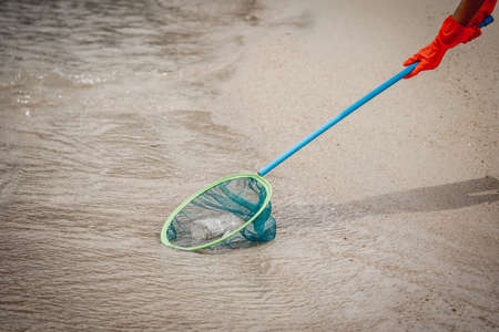 A female ecologist volunteer cleans the beach on the seashore from plastic and other wasteの写真素材